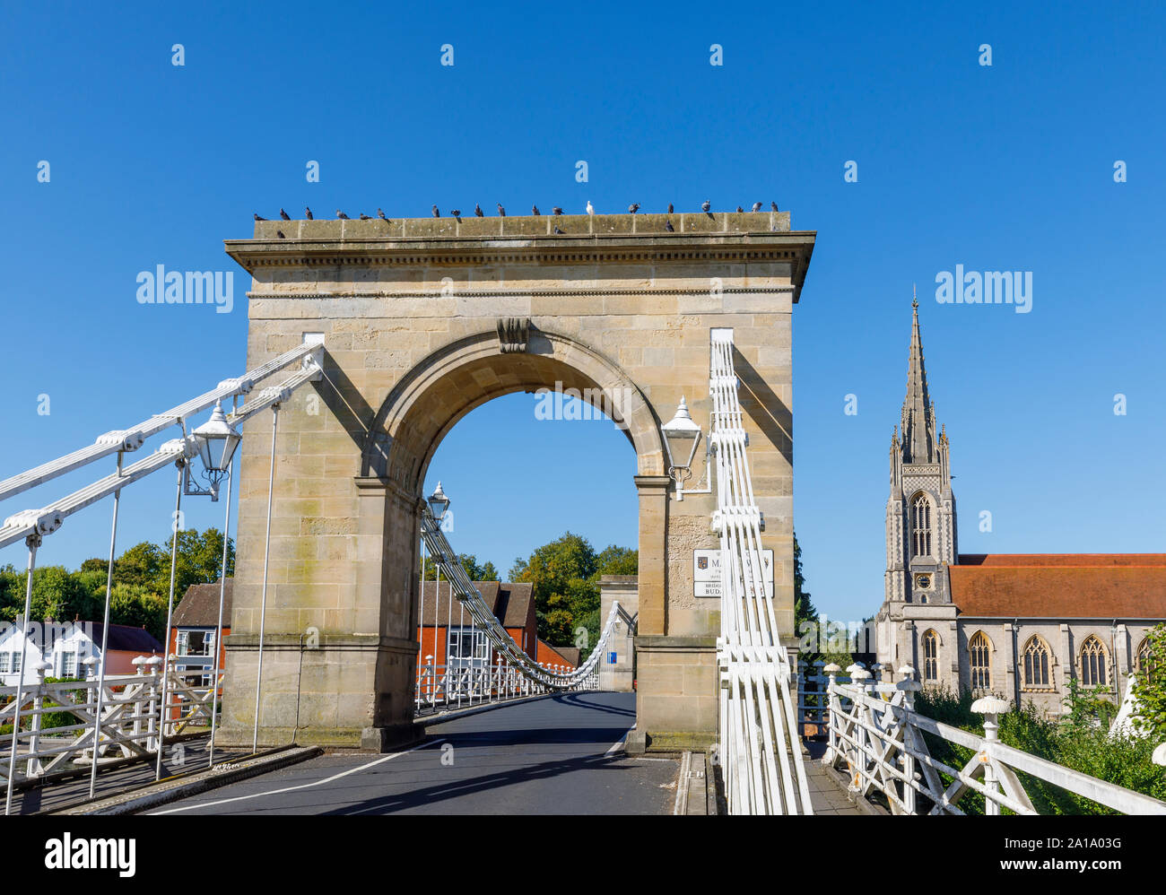 The southern tower entrance arch of Marlow suspension bridge over the River Thames, Marlow, Buckinghamshire, southeast England and All Saints Church Stock Photo