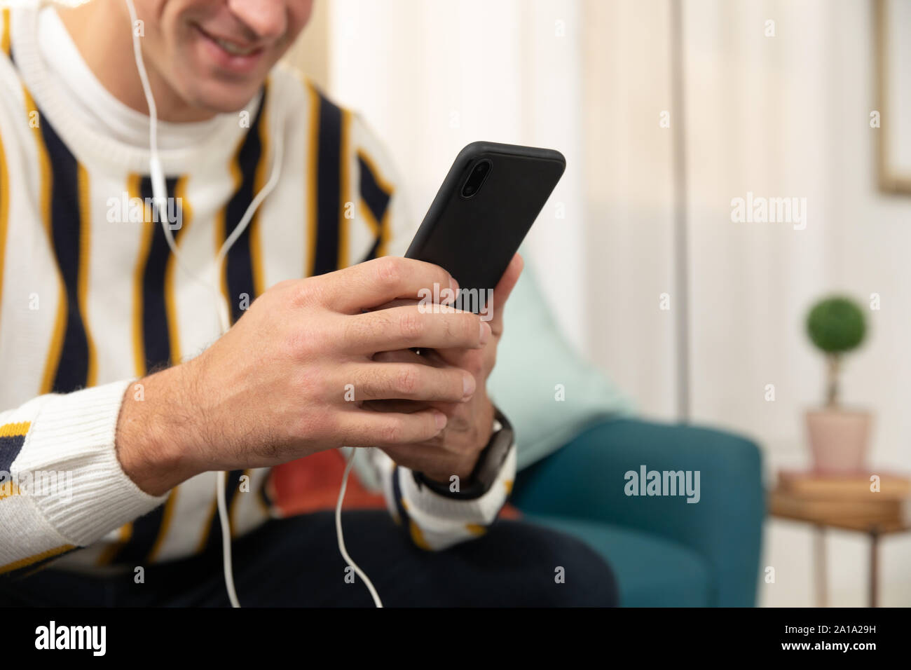 Young man at home using a smartphone Stock Photo