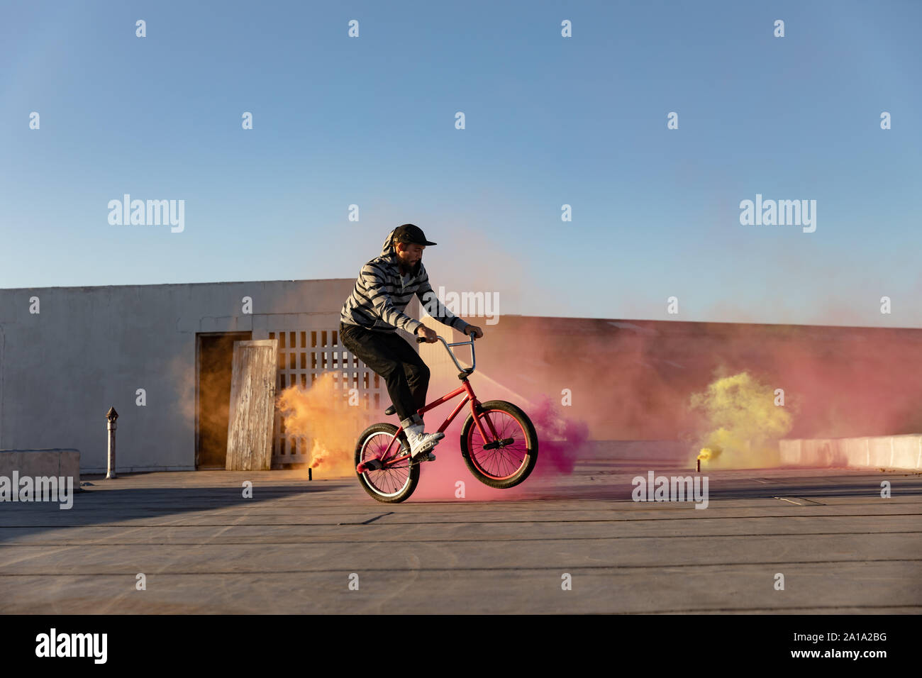 BMX rider on a rooftop using smoke grenades Stock Photo
