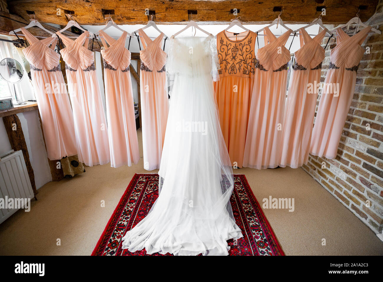 Brides and Bridesmaids dresses hanging in a row on an oak wooden beam ...