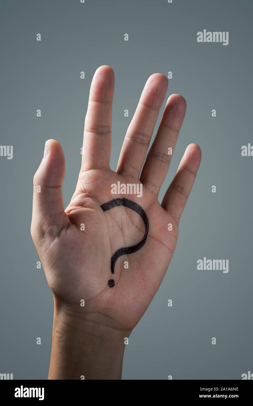 man with a question mark painted in the palm of his hand on an off-white background Stock Photo