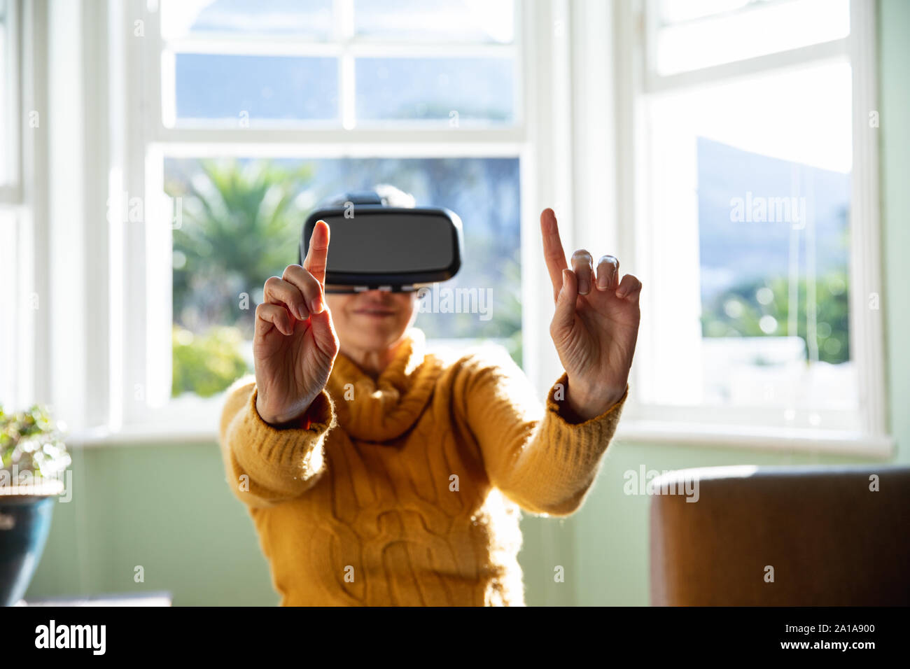 Mature woman alone at home in VR headset Stock Photo - Alamy