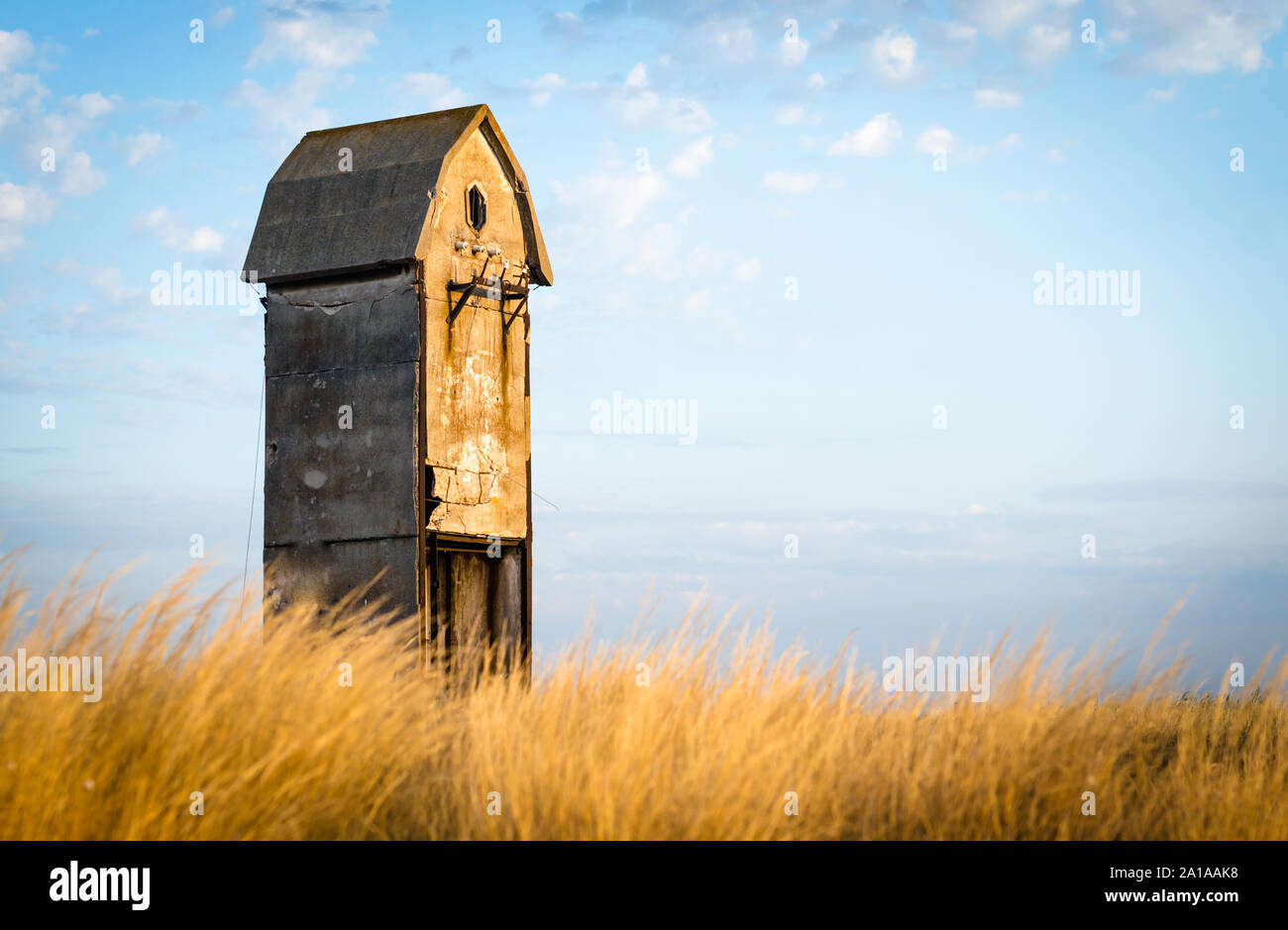 old unusual house in a field against a background of blue sky and ...