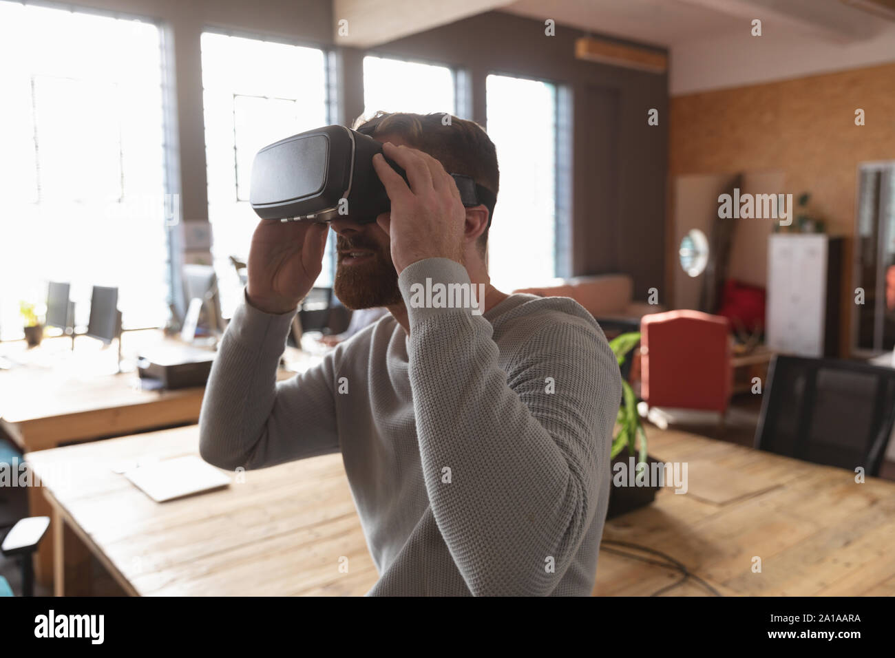 Young creative professional man using VR headset in a sunlit office Stock Photo