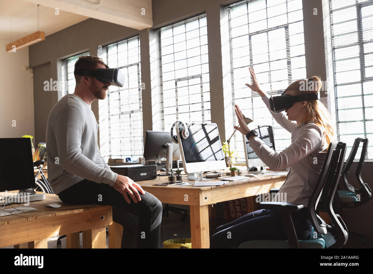 Young creative professionals using VR headsets in a sunlit office Stock Photo