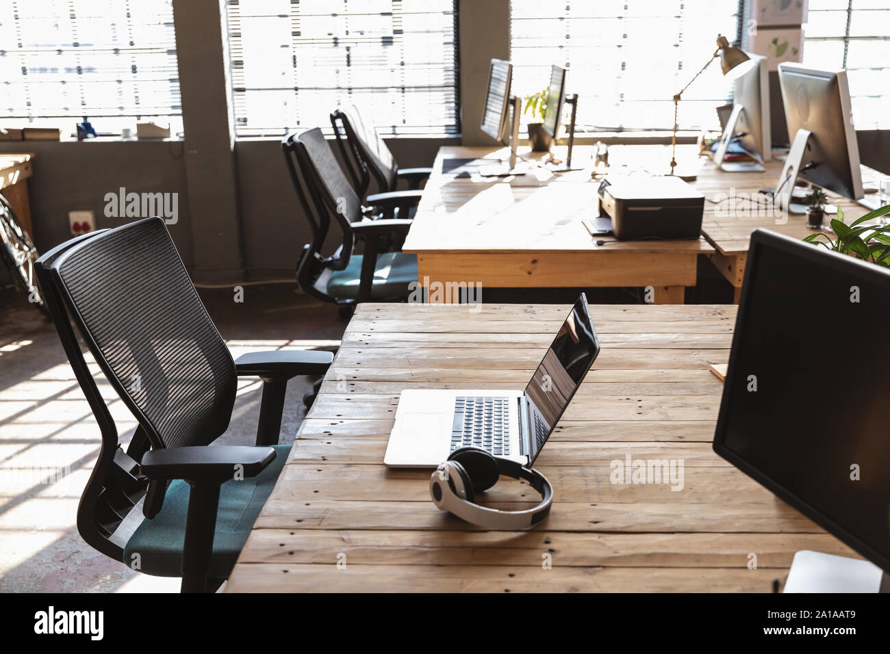 Desks and computers in a sunlit creative office Stock Photo