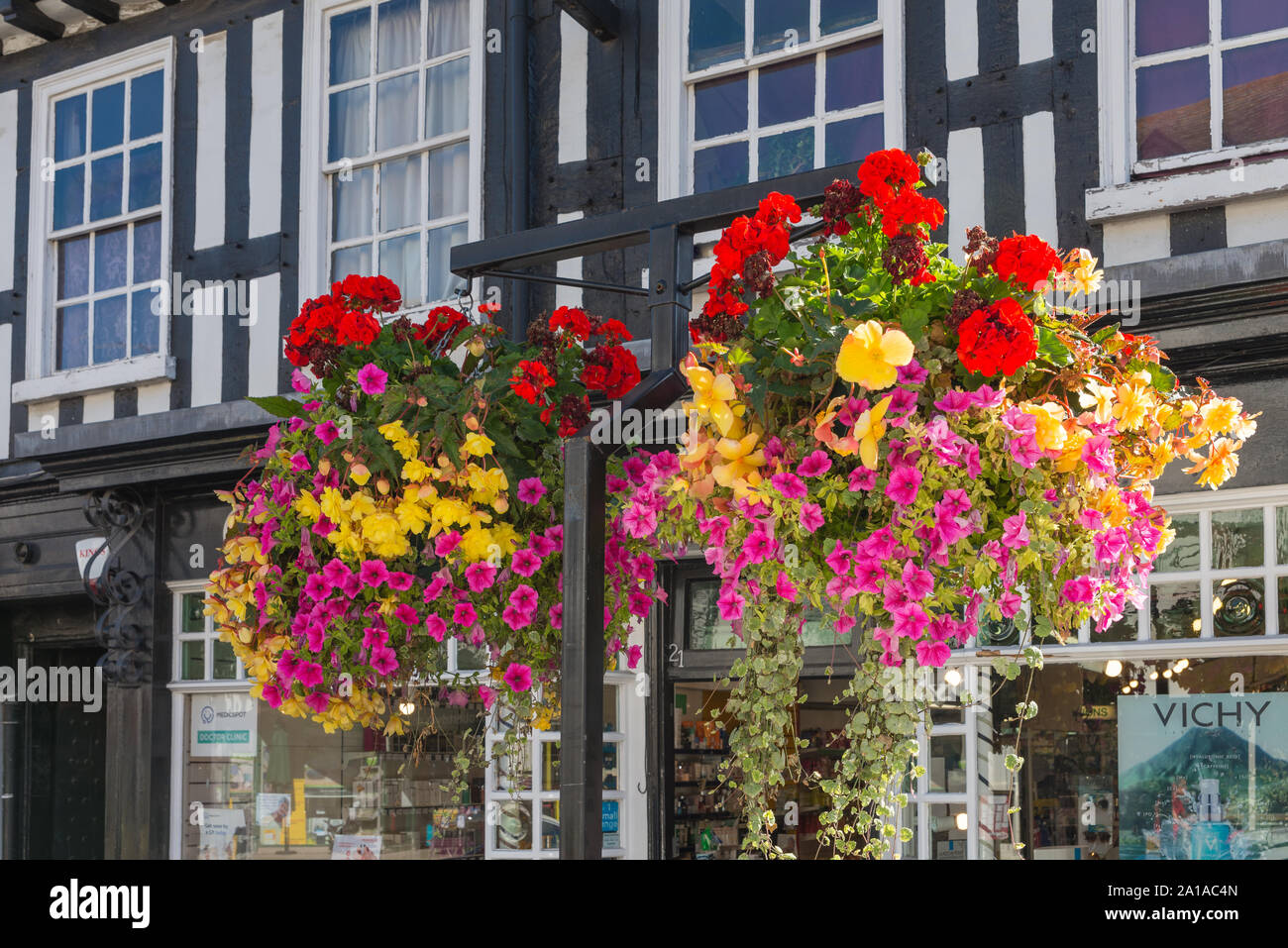 Colourful hanging basket displays on posts in late summer sunshine in