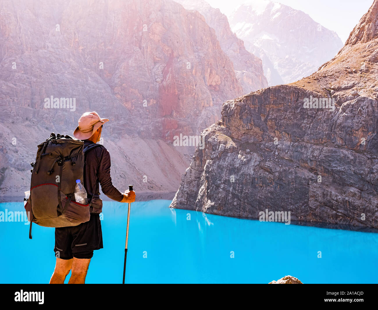 Man with backpack near lake Big Alo on rocky mountain background. Fann Mountains, Tajikistan, Central Asia Stock Photo