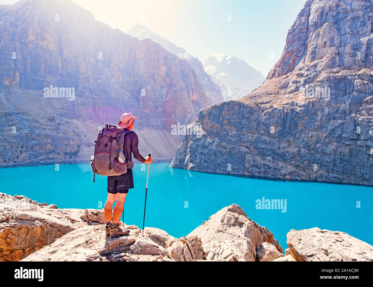 Man with backpack near lake Big Alo on rocky mountain background. Fann Mountains, Tajikistan, Central Asia Stock Photo