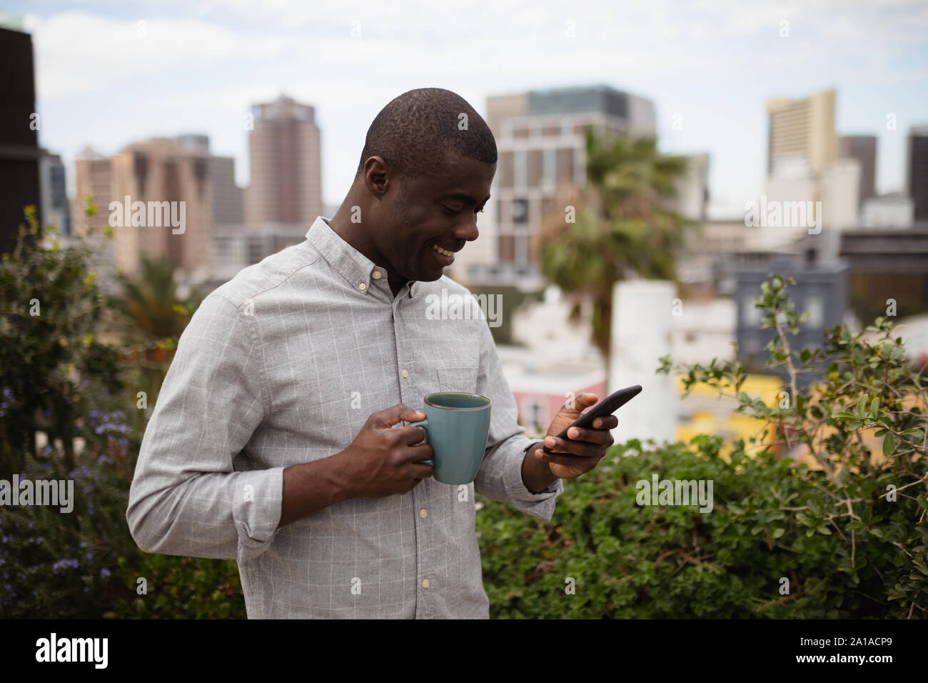 Young man using smartphone on a balcony Stock Photo