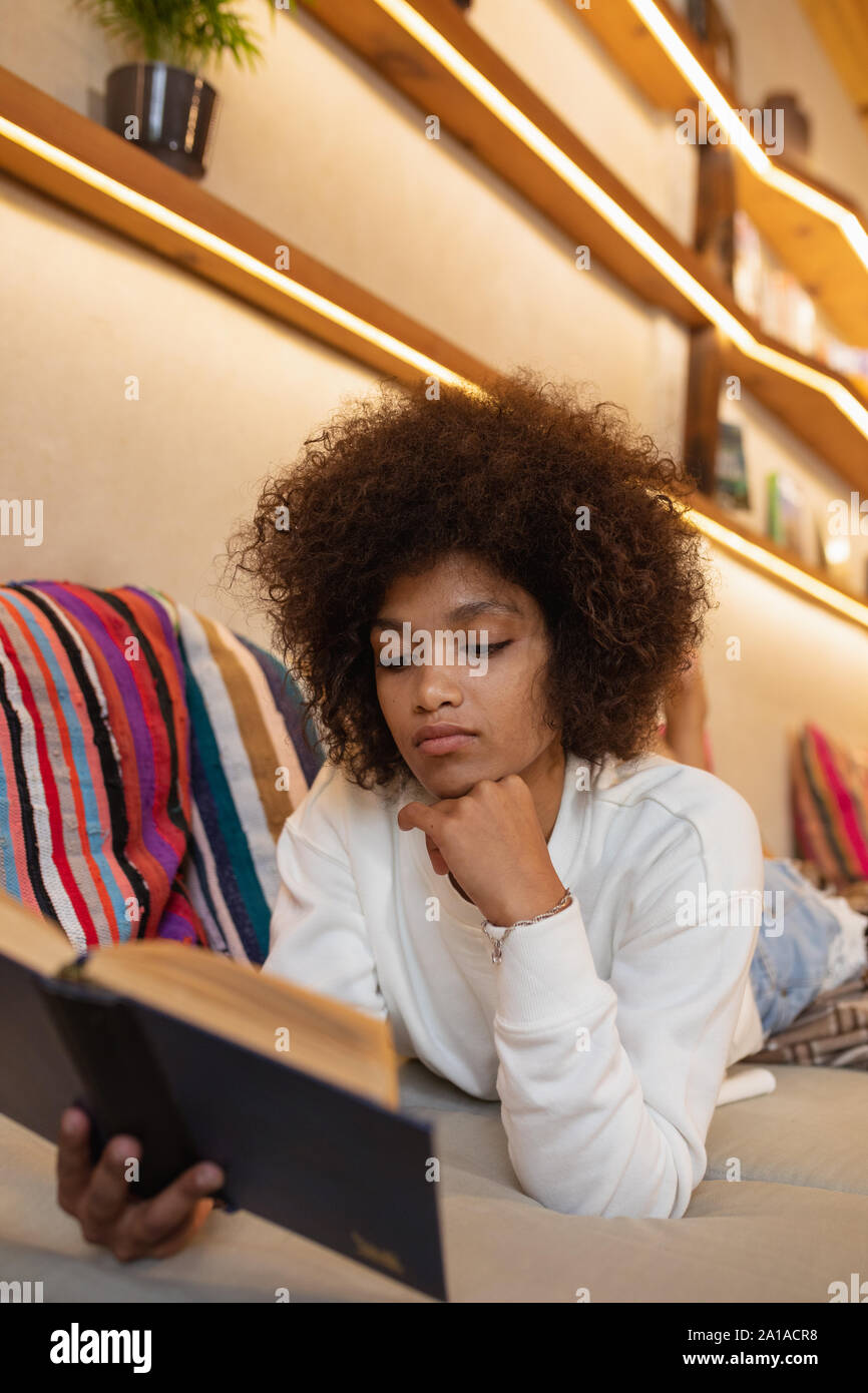 Woman reading lying on a sofa Stock Photo