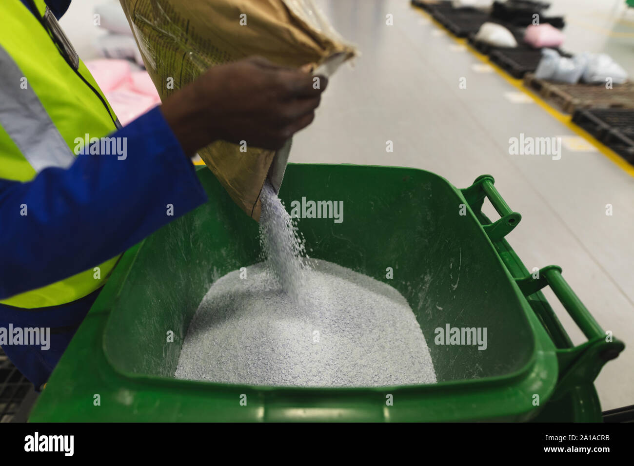 Factory worker pouring granules into bin Stock Photo