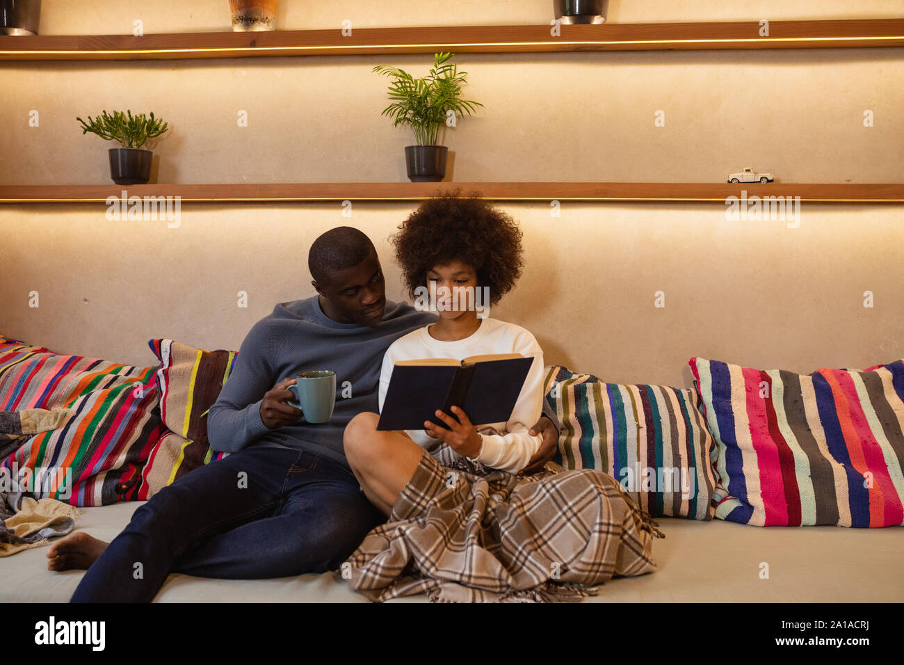 Couple reading a book on a sofa Stock Photo