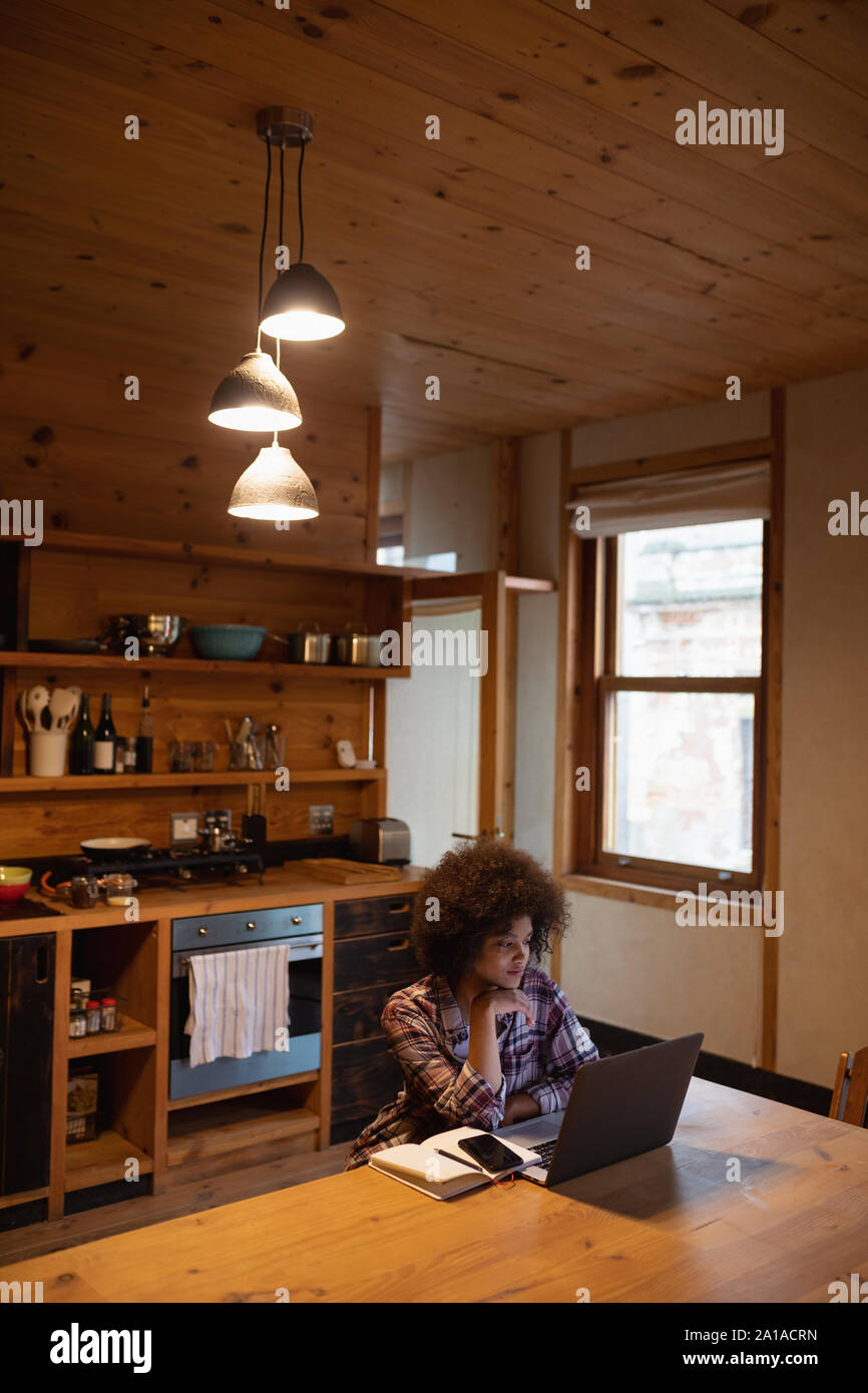 Young woman using laptop in a kitchen Stock Photo