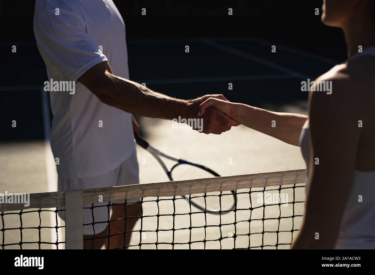 Woman and man shaking hands at a tennis court Stock Photo