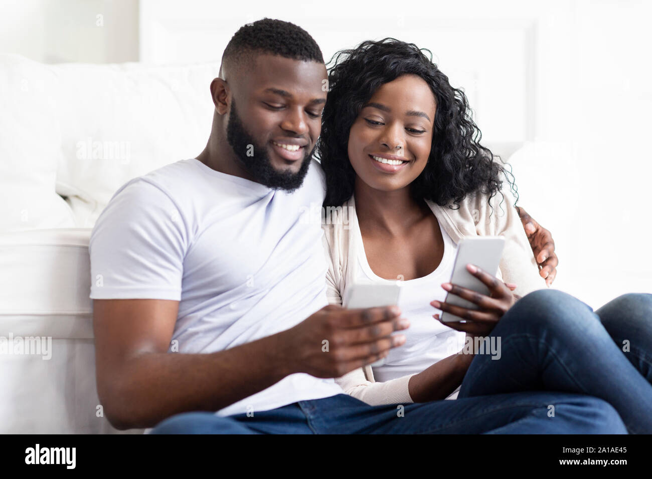 Boyfriend and girlfriend reading messages in each other's cellphones Stock Photo