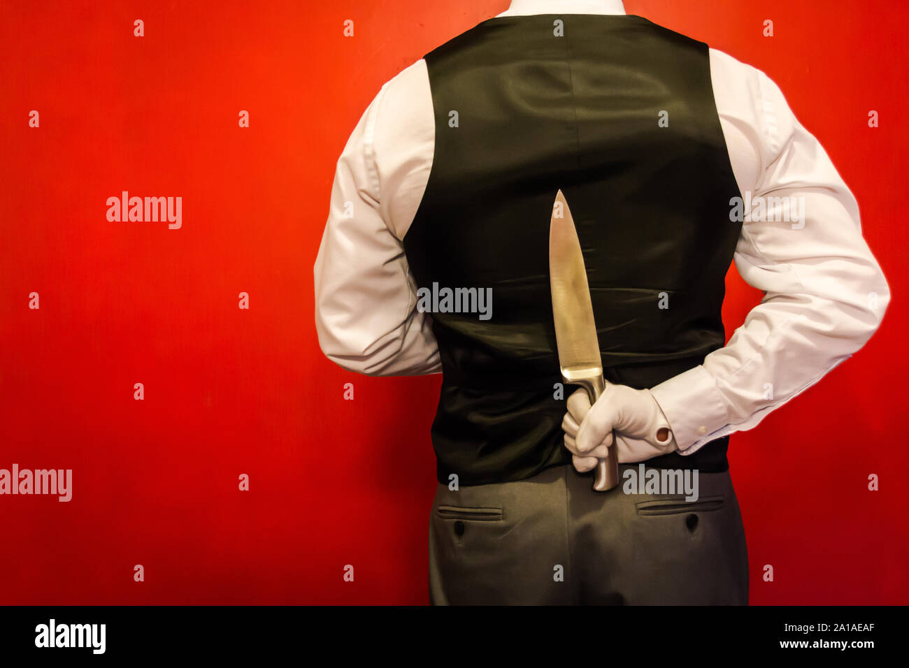 Butler Holding Knife Behind His Back. Concept of Surprise and Danger. Horror Movie Murderer.. Copy Space for Horror Film. Dark Stock Photo. Stock Photo
