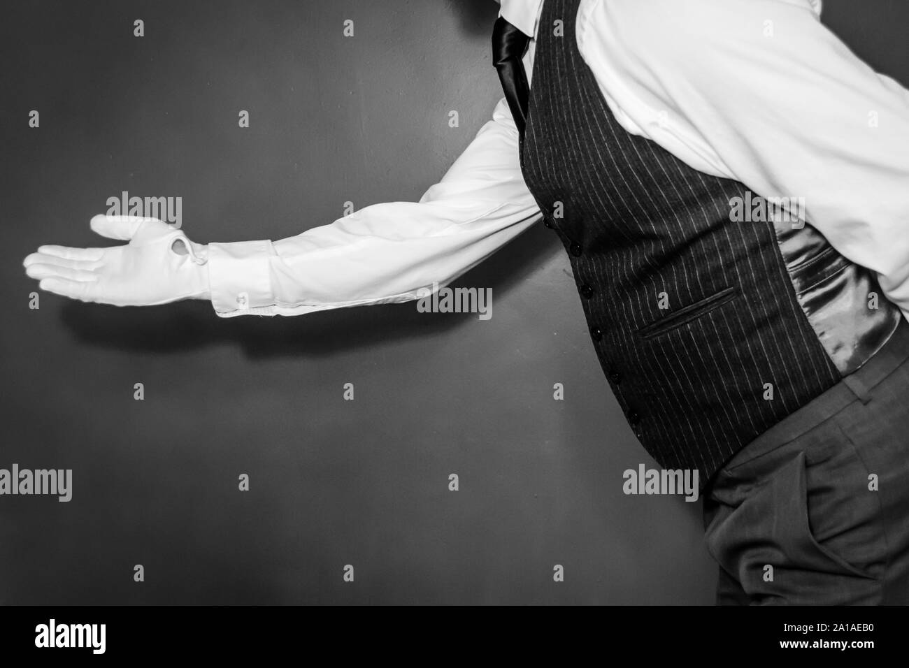 Butler in White Gloves With Welcoming Gesture. Concept of Service Industry and Professional Hospitality and Courtesy. Stock Photo