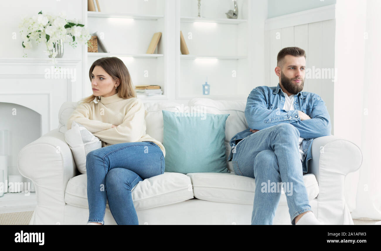 Young couple sitting on different sides of couch after quarrel Stock Photo