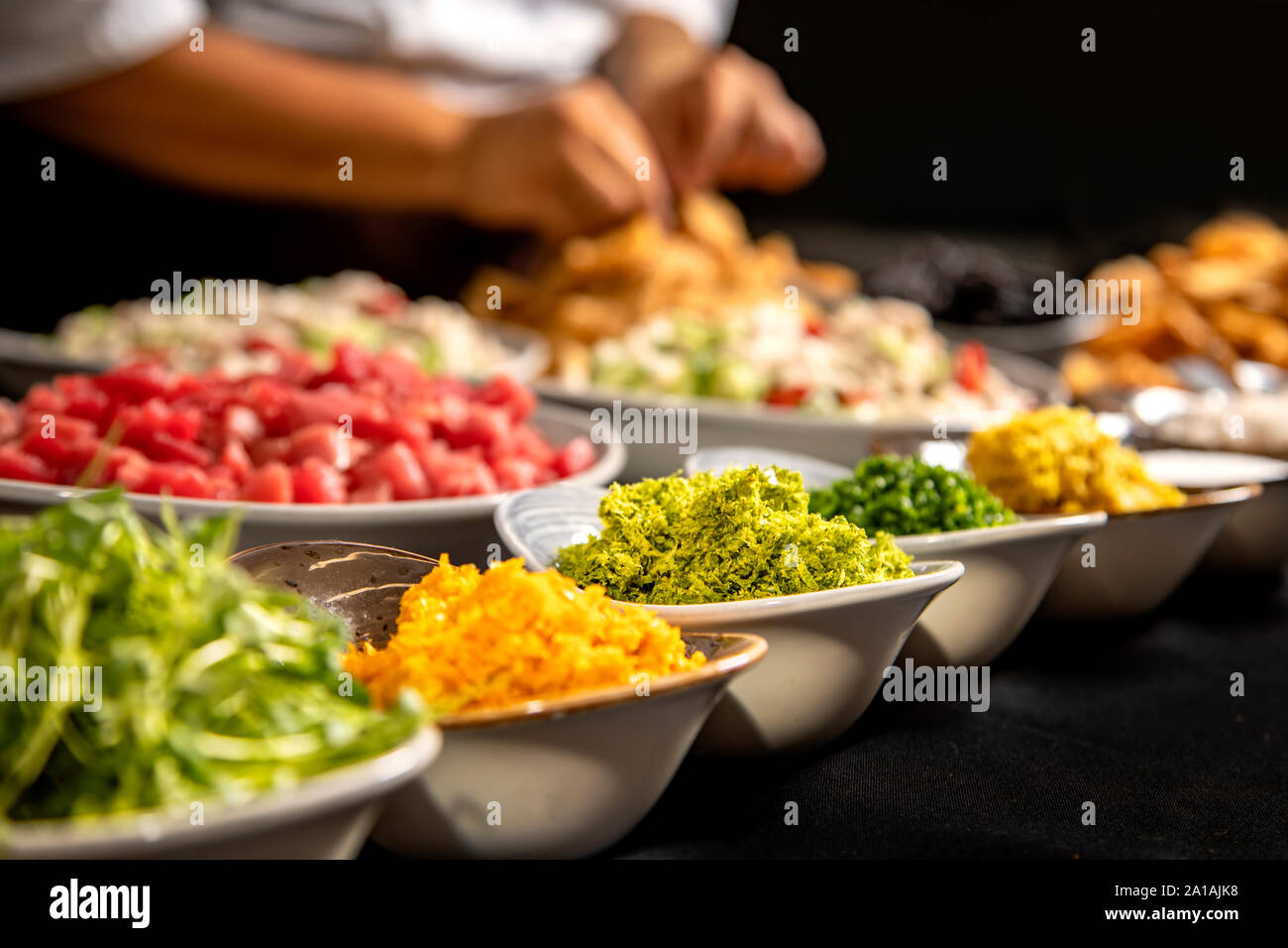 Spices in bowls with chef's hands working in background Stock Photo