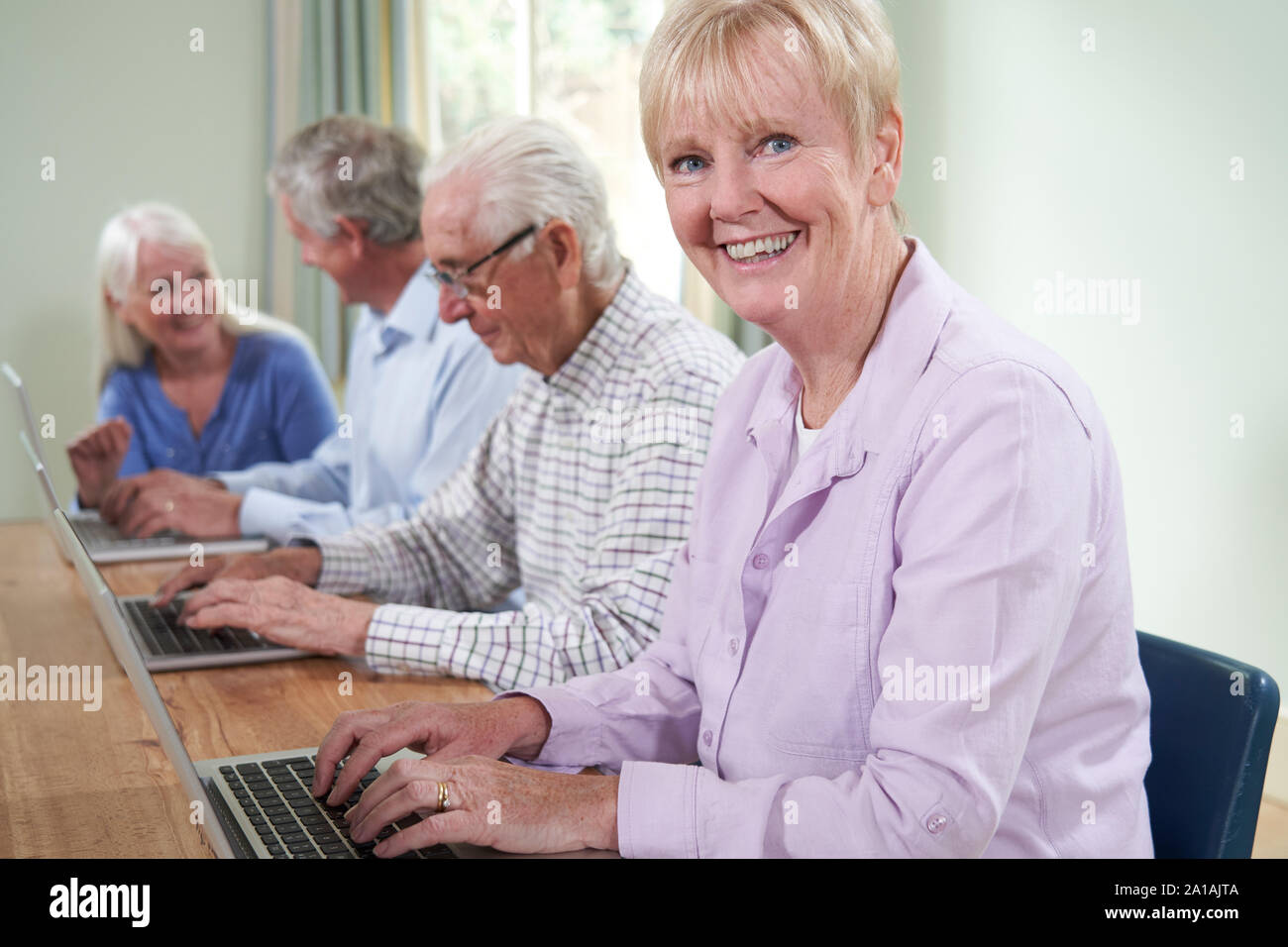 Portrait Of Senior Woman With Tutor In Computer Class Stock Photo