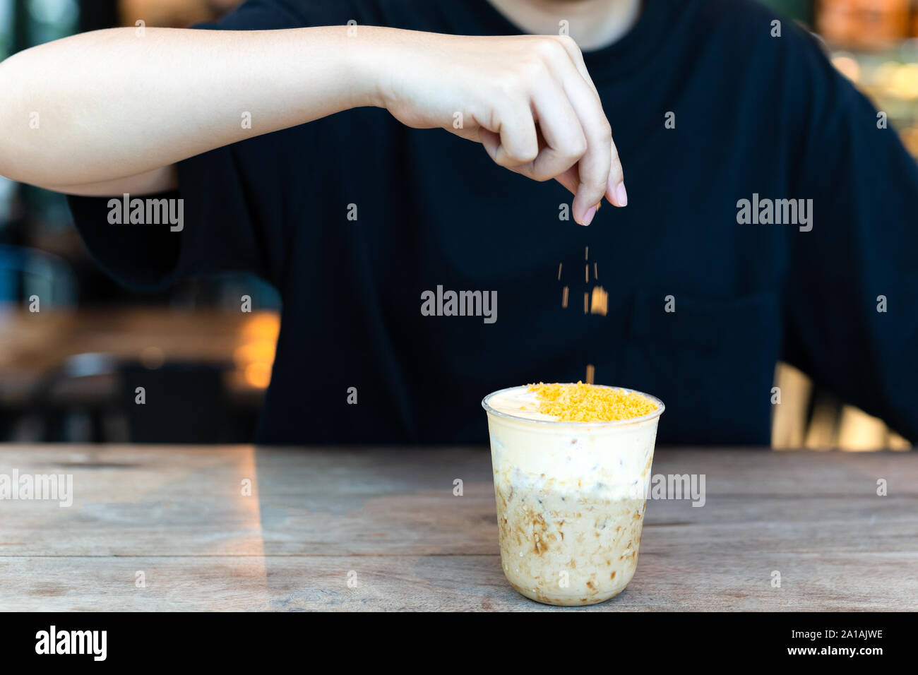 Barista making iced milk tea with salty egg at cafe. Stock Photo