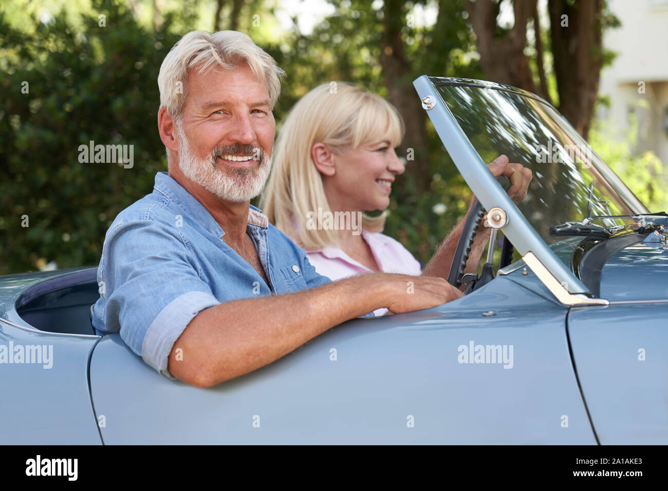 Portrait Of Mature Couple Enjoying Road Trip In Classic Open Top Sports Car Together Stock Photo