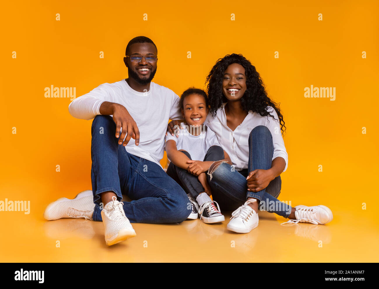 Portrait of happy black family smiling over yellow studio background ...