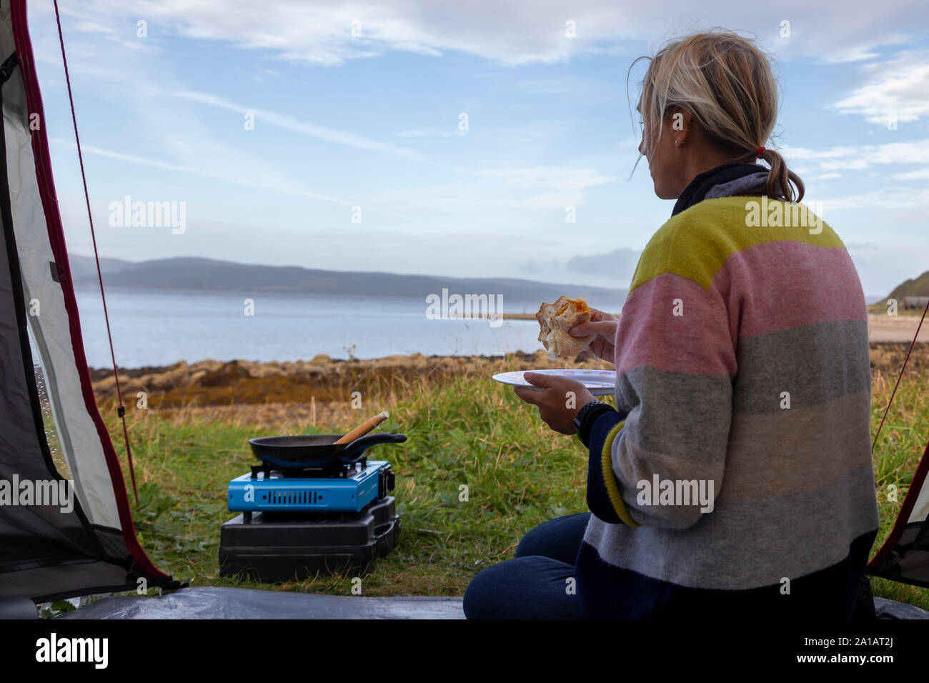 eating an egg roll at the seaside wild camping Stock Photo