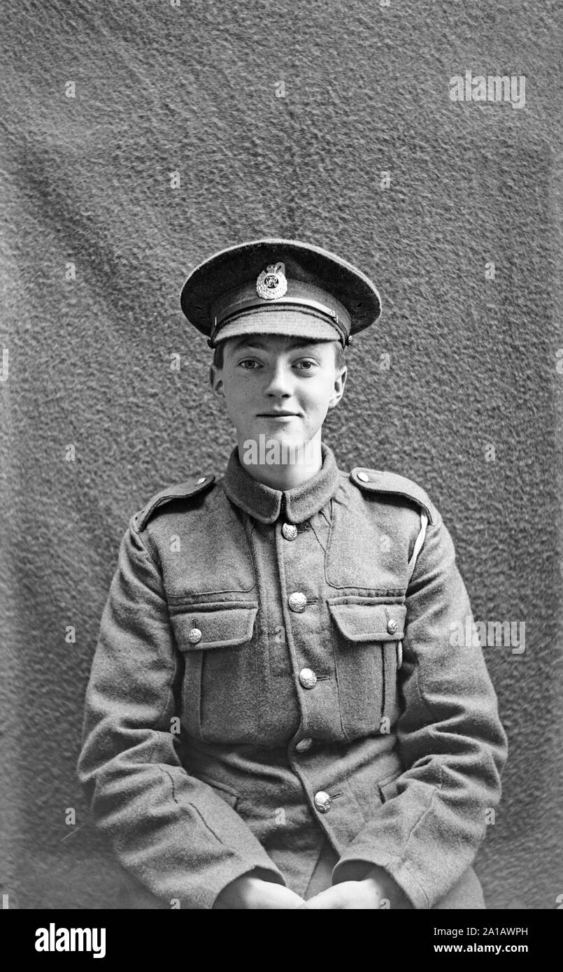 A vintage British Studio black and white portrait photograph of a very young man in a soldiers uniform, taken between 1914 and 1918, during the years of the First World war. The boy is smiling and looks happy. Stock Photo