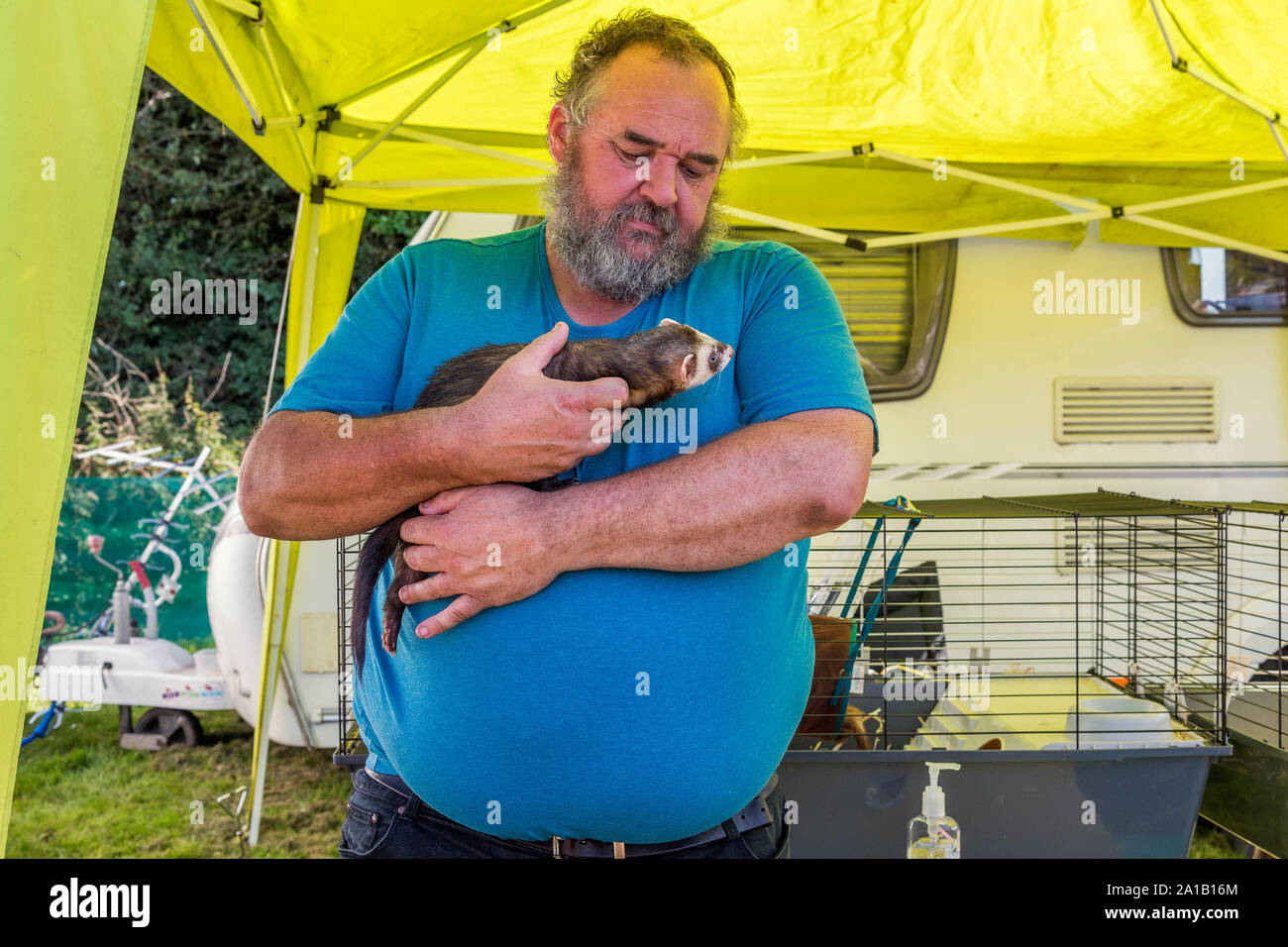 A bearded man affectionately holding his pet ferret. Stock Photo