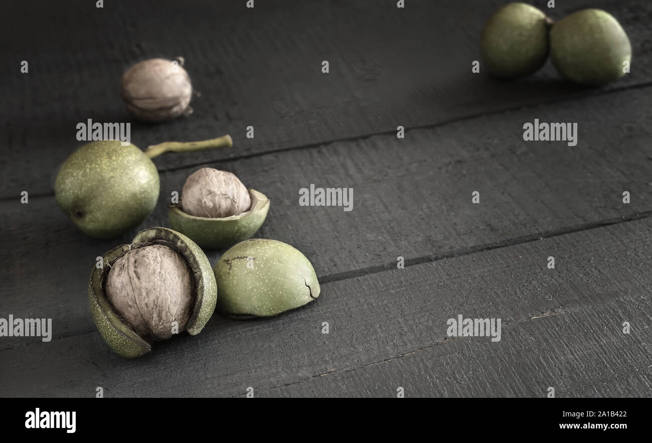 Walnuts in a green shell on a wooden table Stock Photo