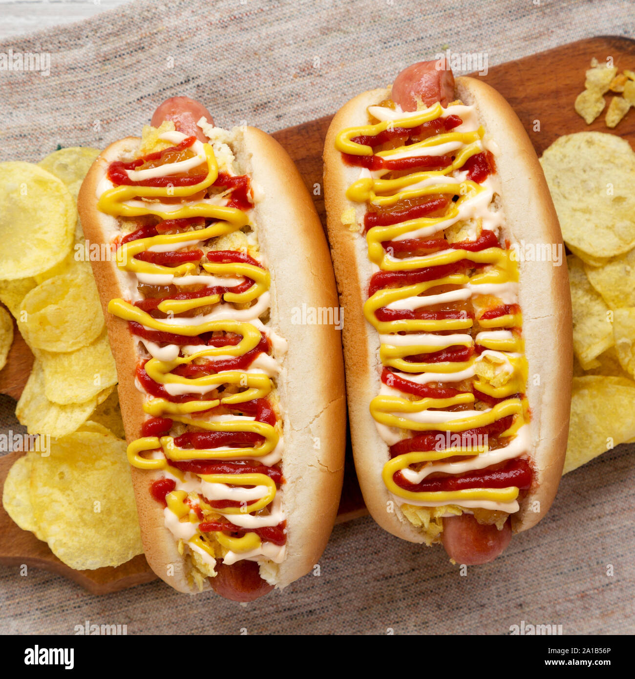 Homemade colombian hot dogs with pineapple sauce, yellow mustard and mayo ketchup on a rustic wooden board, overhead view. Flat lay, top view, overhea Stock Photo