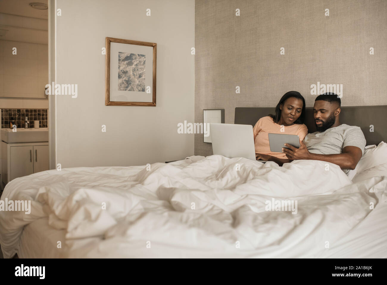 Smiling African American couple browsing on line in bed Stock Photo - Alamy