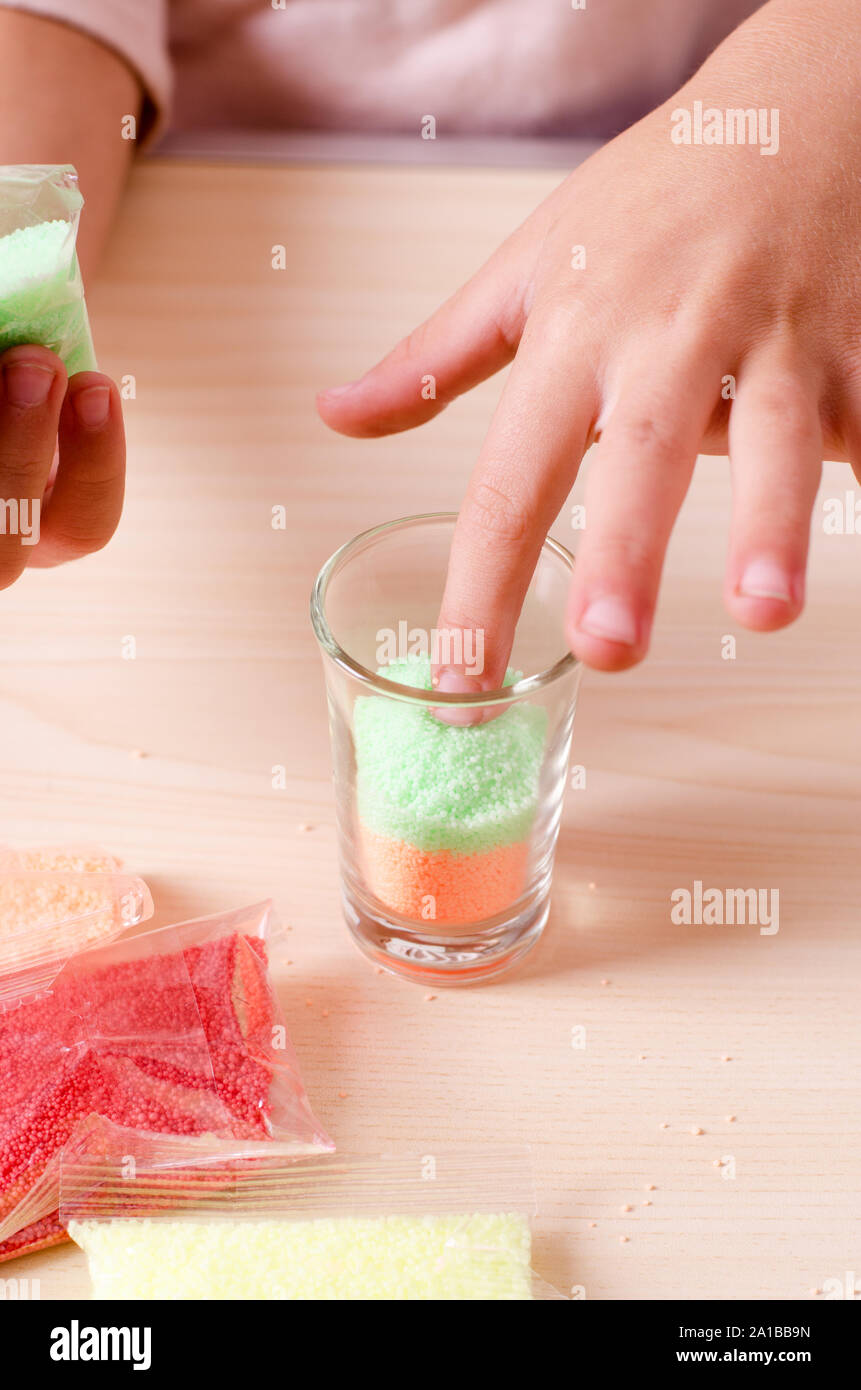 Making candles by yourself process. Little girl making candle in the glass from soy wax parsley