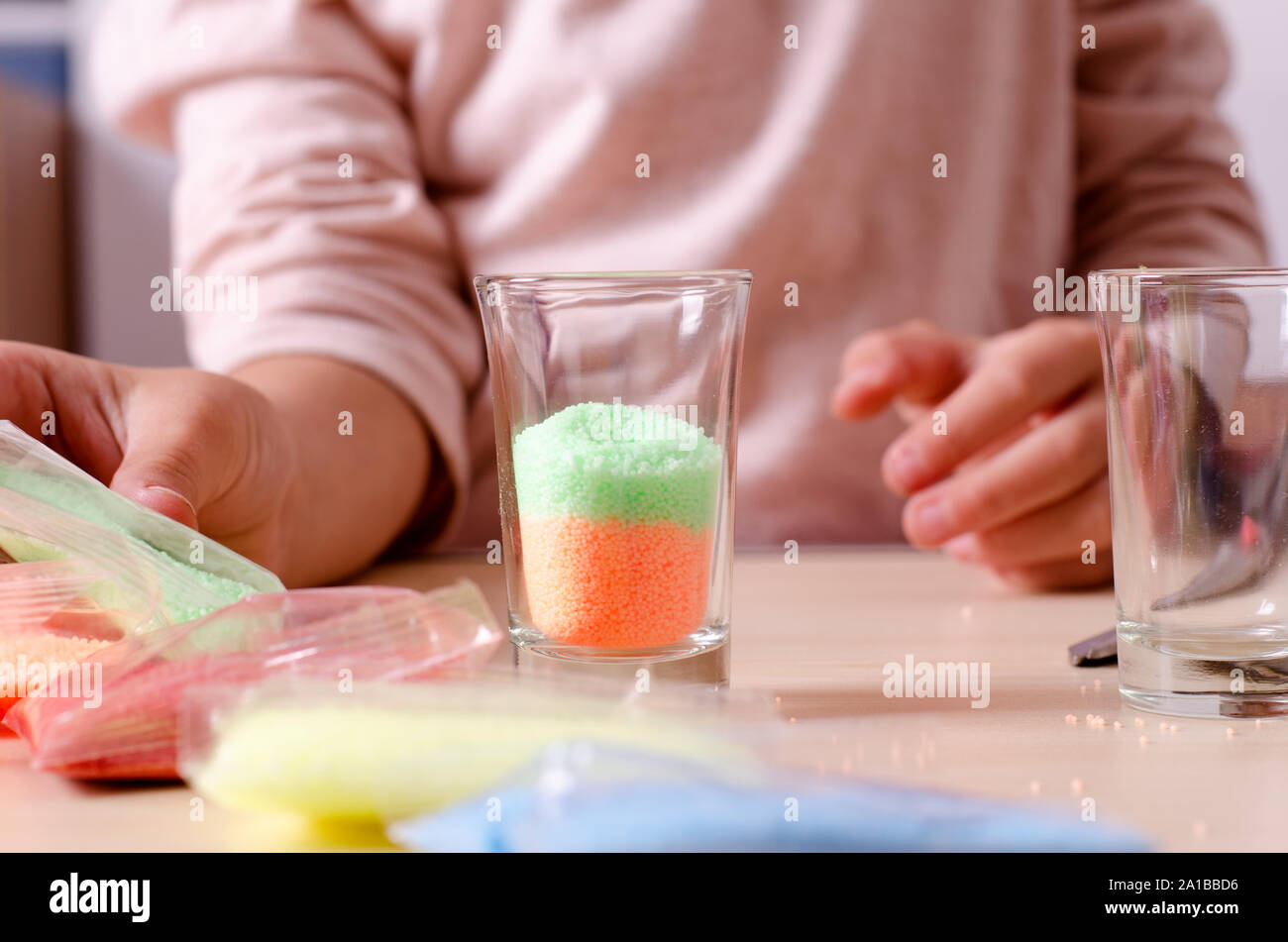 Making candles by yourself process. Little girl making candle in the glass from soy wax parsley