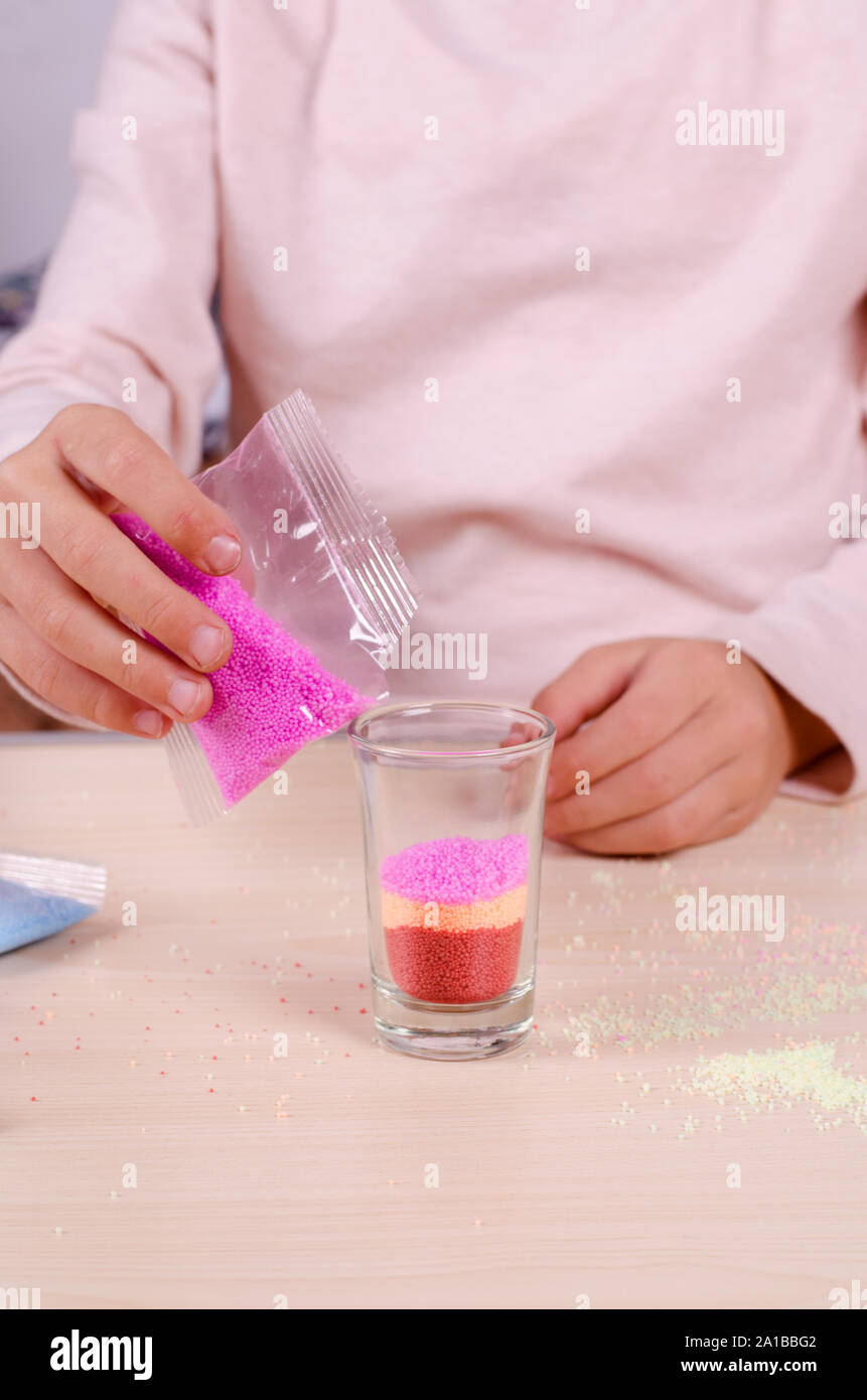 Making candles by yourself process. Little girl making candle in the glass from soy wax parsley