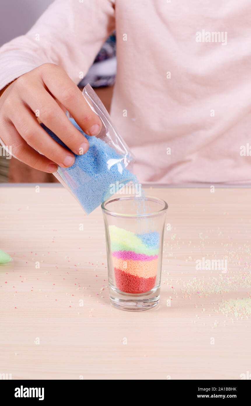 Making candles by yourself process. Little girl making candle in the glass from soy wax parsley