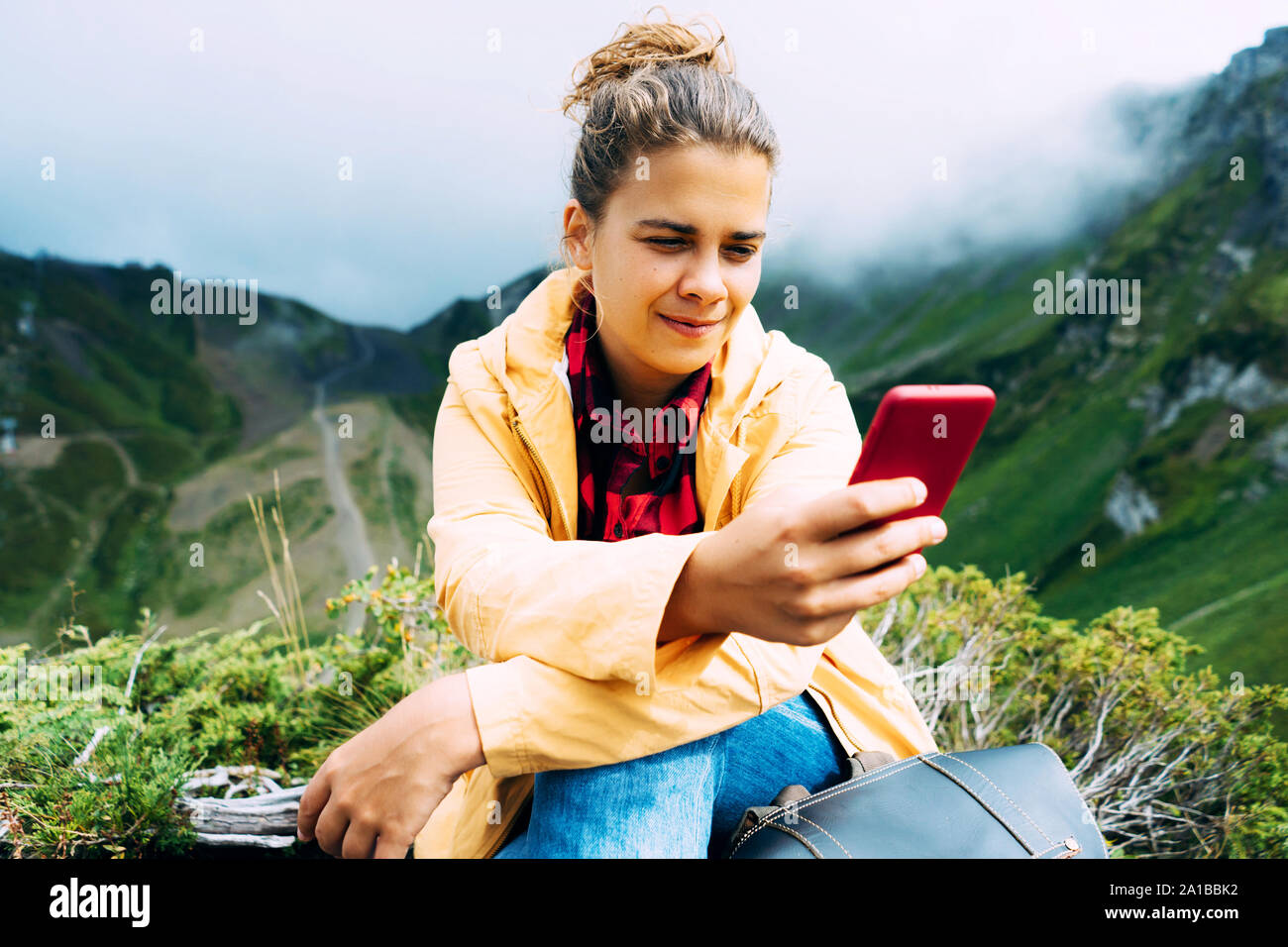 woman reads sms and looks at a mobile phone in the mountains. Stock Photo