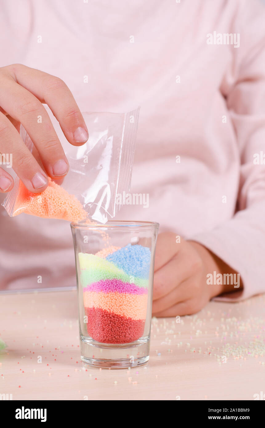 Making candles by yourself process. Little girl making candle in the glass from soy wax parsley