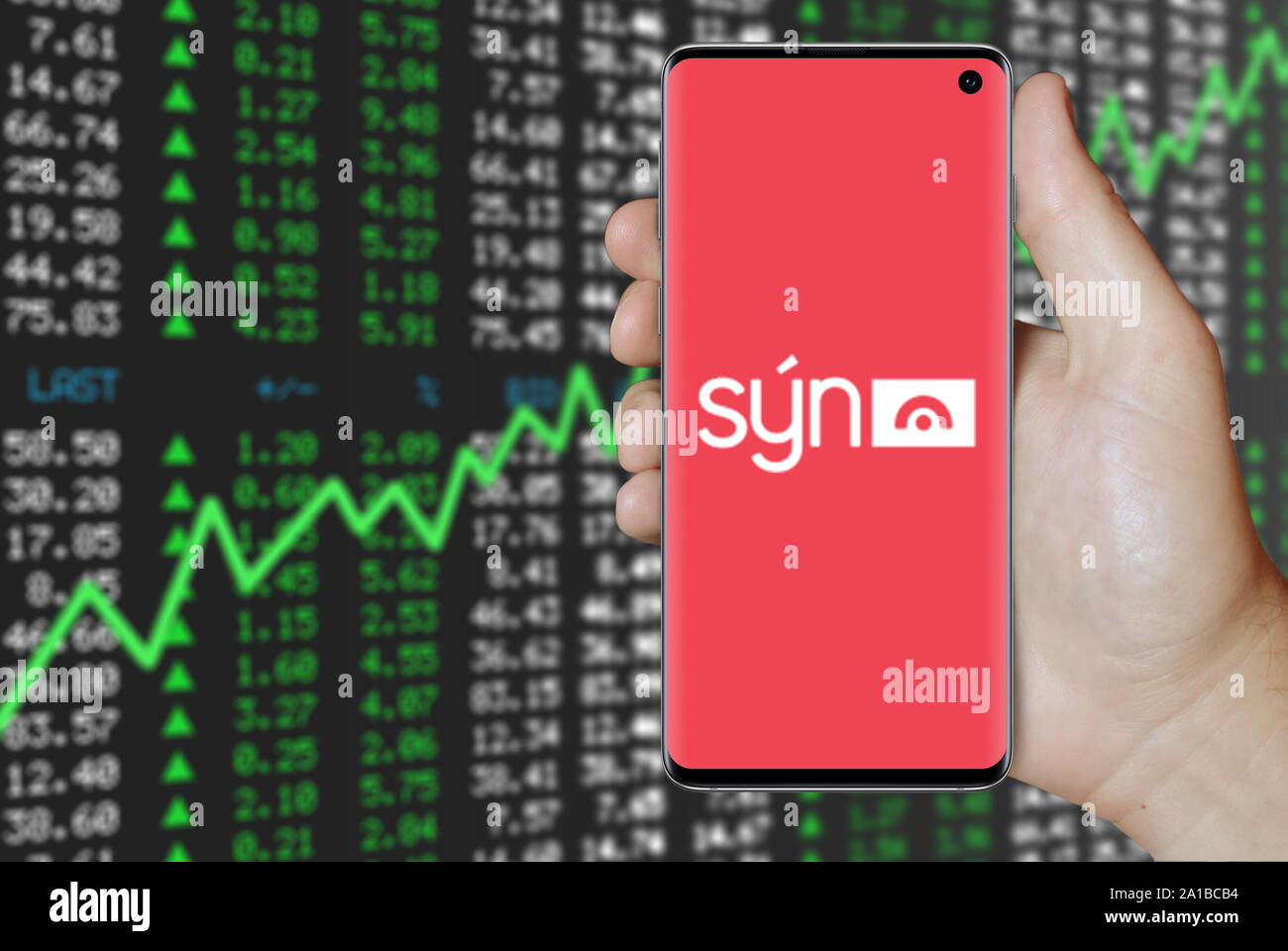 A man holds a smartphone displaying the logo of company Sýn listed on Nasdaq Iceland. Positive stock market background. Credit: PIXDUCE Stock Photo