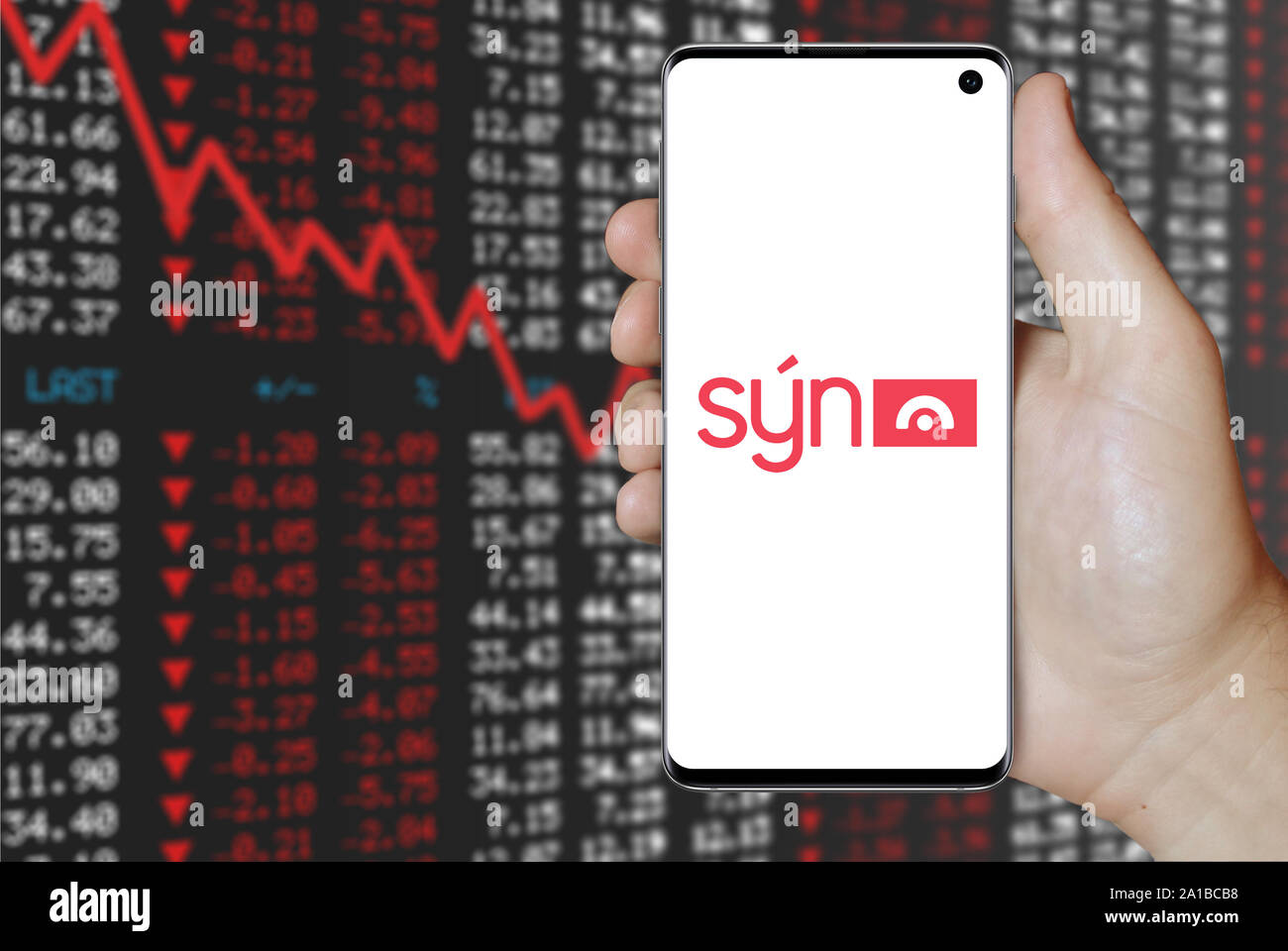 A man holds a smartphone displaying the logo of company Sýn listed on Nasdaq Iceland. Negative stock market background. Credit: PIXDUCE Stock Photo