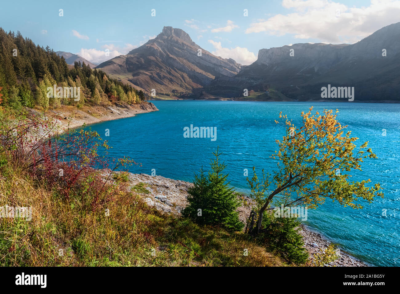 Sunny day on Roselend lake (Lac de Roselend) in France Alps. Blue water and high mountains in background. Landscape photography Stock Photo