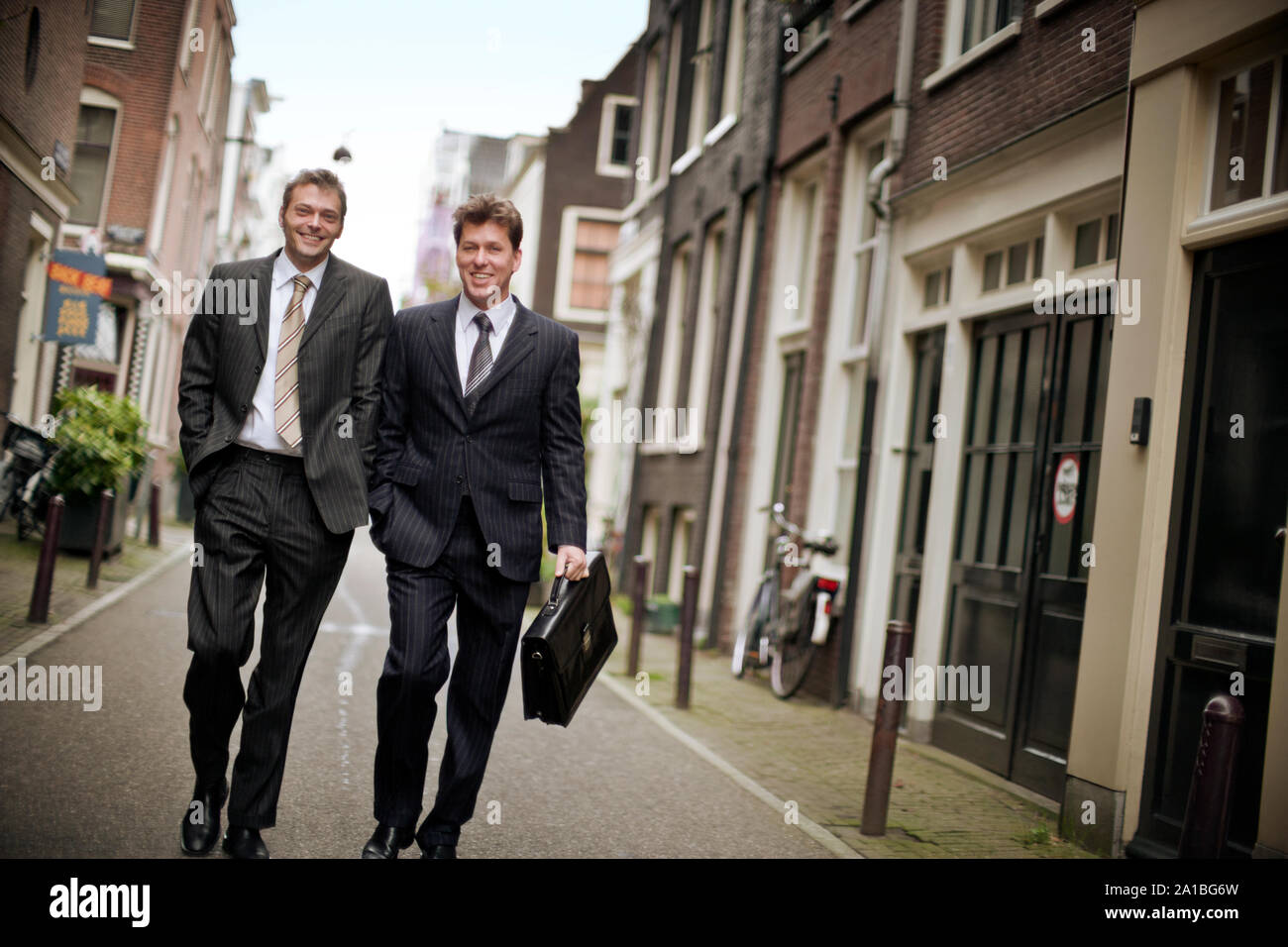 Two businessmen smile and talk as they walk down a side street Stock ...