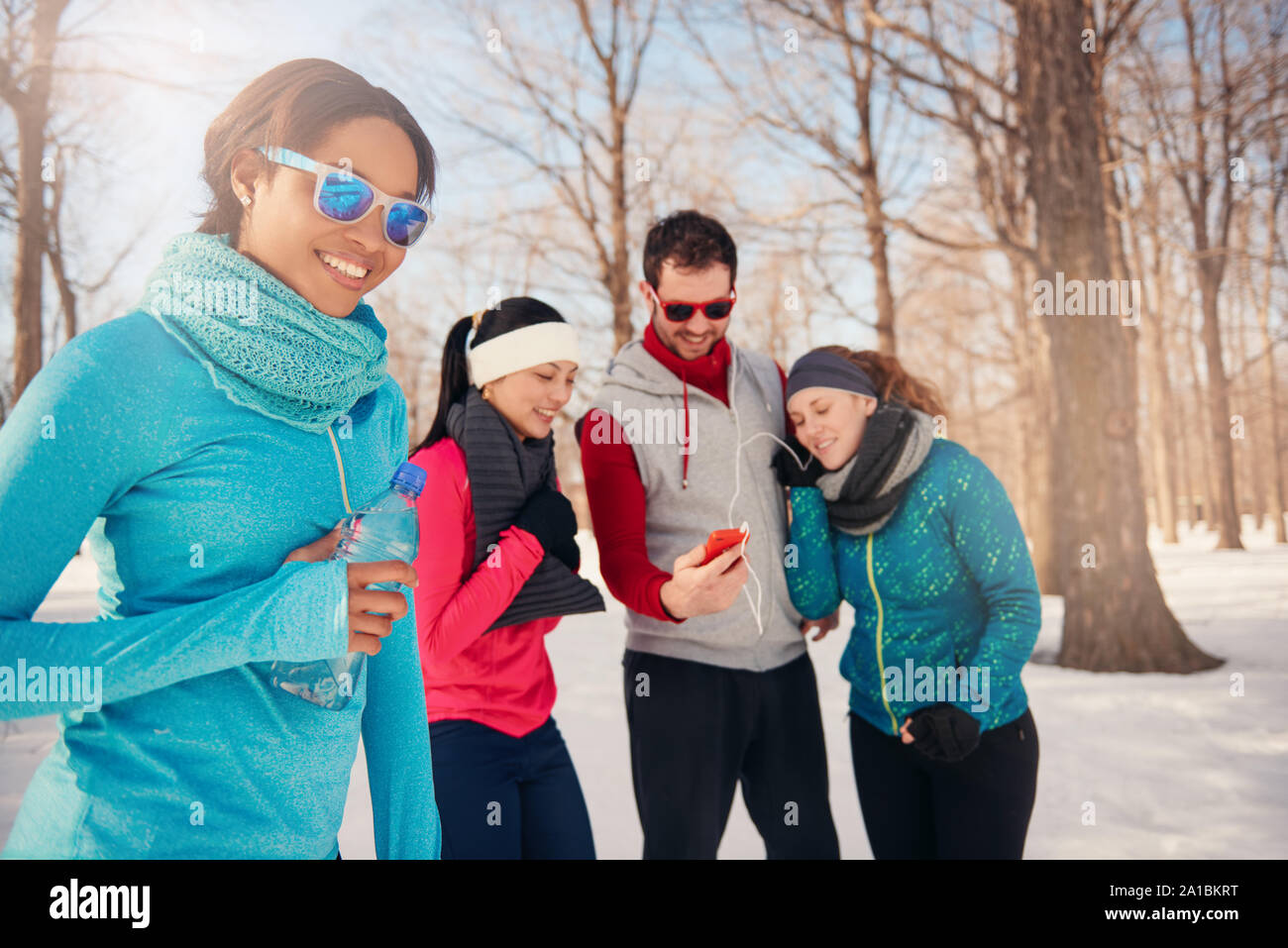 Group of friends listening to music in the snow in winter Stock Photo