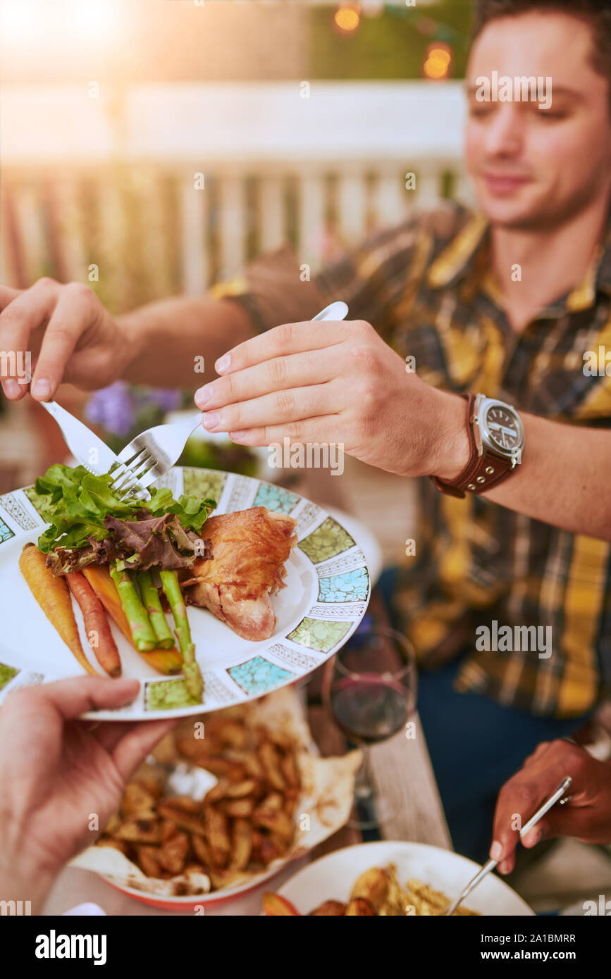 Group of diverse friends serving a balanced dinner al fresco in urban setting Stock Photo