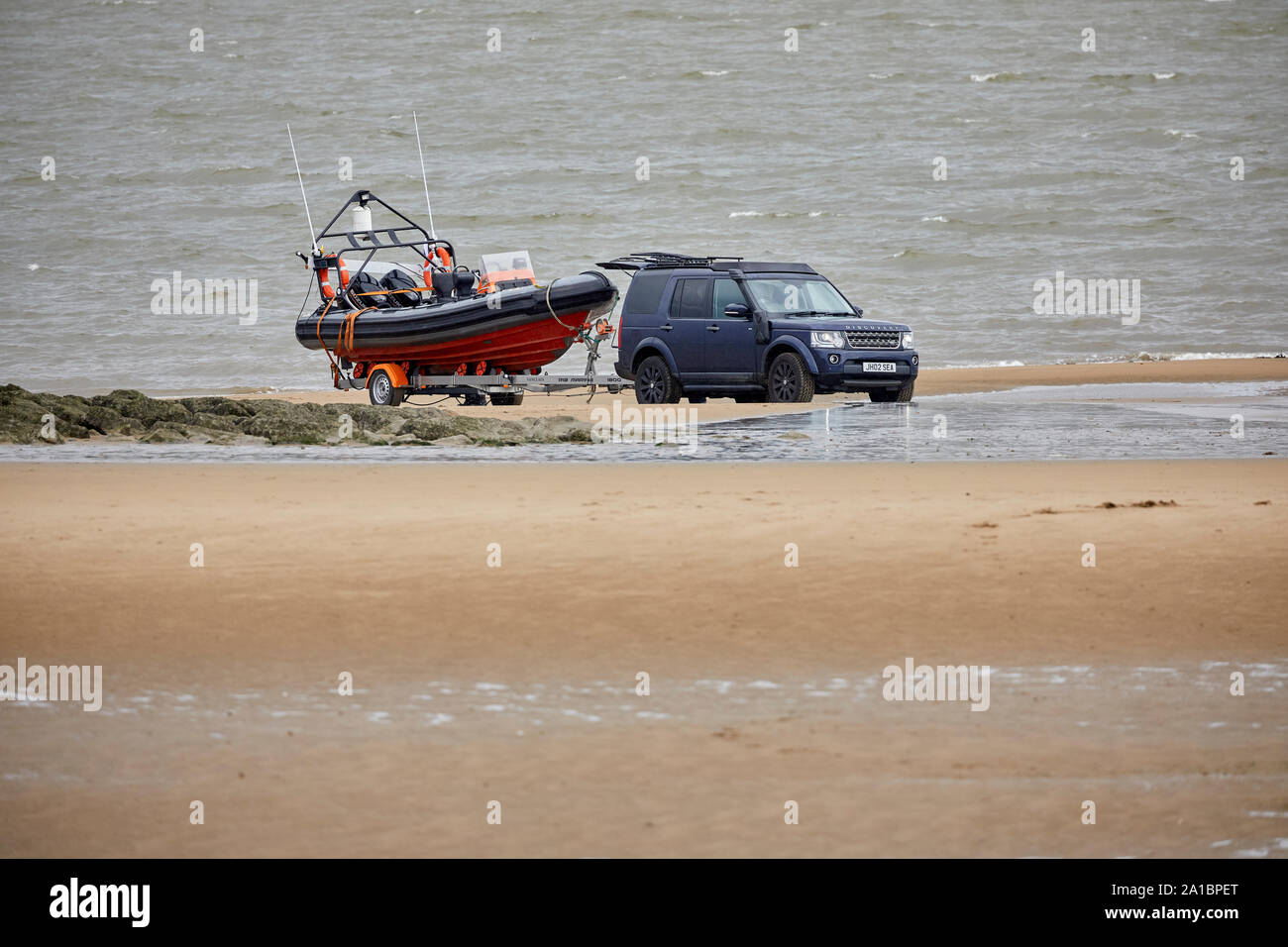 A Land Rover Discovery hooked up to a  speed boat no the sand at New Brighton waterfront beach Stock Photo