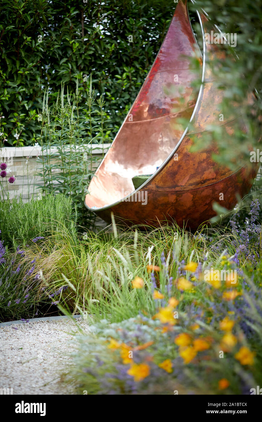 Modern luxury relaxing hanging chair seating made of copper  on decked area of modern garden Stock Photo