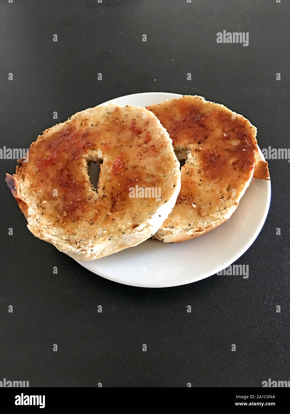 Toasted bagel halves on a white plate Stock Photo