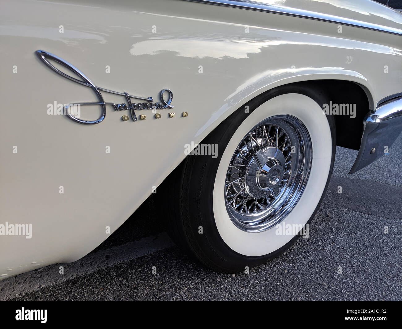 A restored Crown Imperial cursive fender logo and whitewall tire are seen at a vintage car rally. Stock Photo